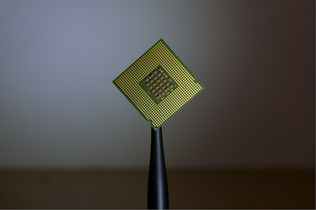 A computer processor chip held by tweezers, representing the new Snapdragon C laptop platform