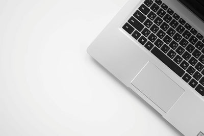 Silver laptop keyboard and trackpad viewed from above on a white desk