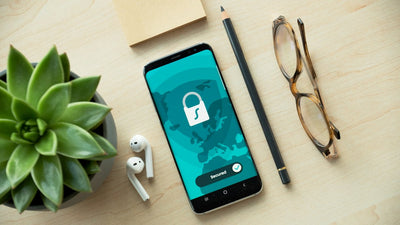 A smartphone displaying a security lock icon on a wooden desk, representing IMEI and device security verification