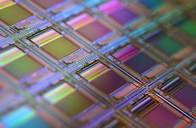 A silicon wafer with a grid of iridescent microchip dies, representing TSMC's advanced chip manufacturing