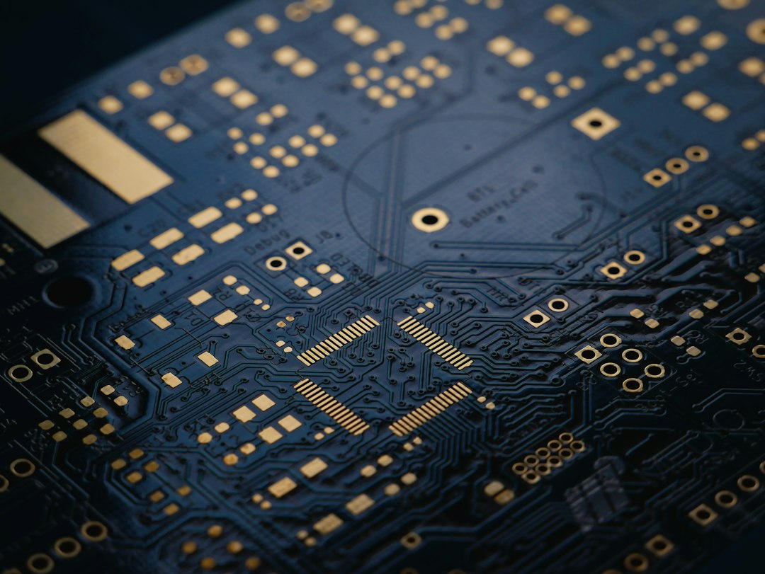 Close-up of a dark blue printed circuit board with gold finish, representing the memory chips driving Samsung's production cuts
