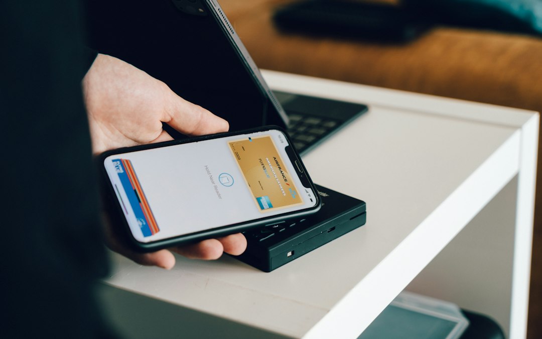 A person holding a smartphone over a payment terminal to make a contactless Apple Pay purchase