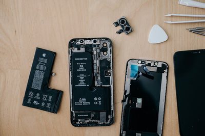 Technician repairing an iPhone on a workbench, illustrating the warranty and repair-cost issues covered in this article